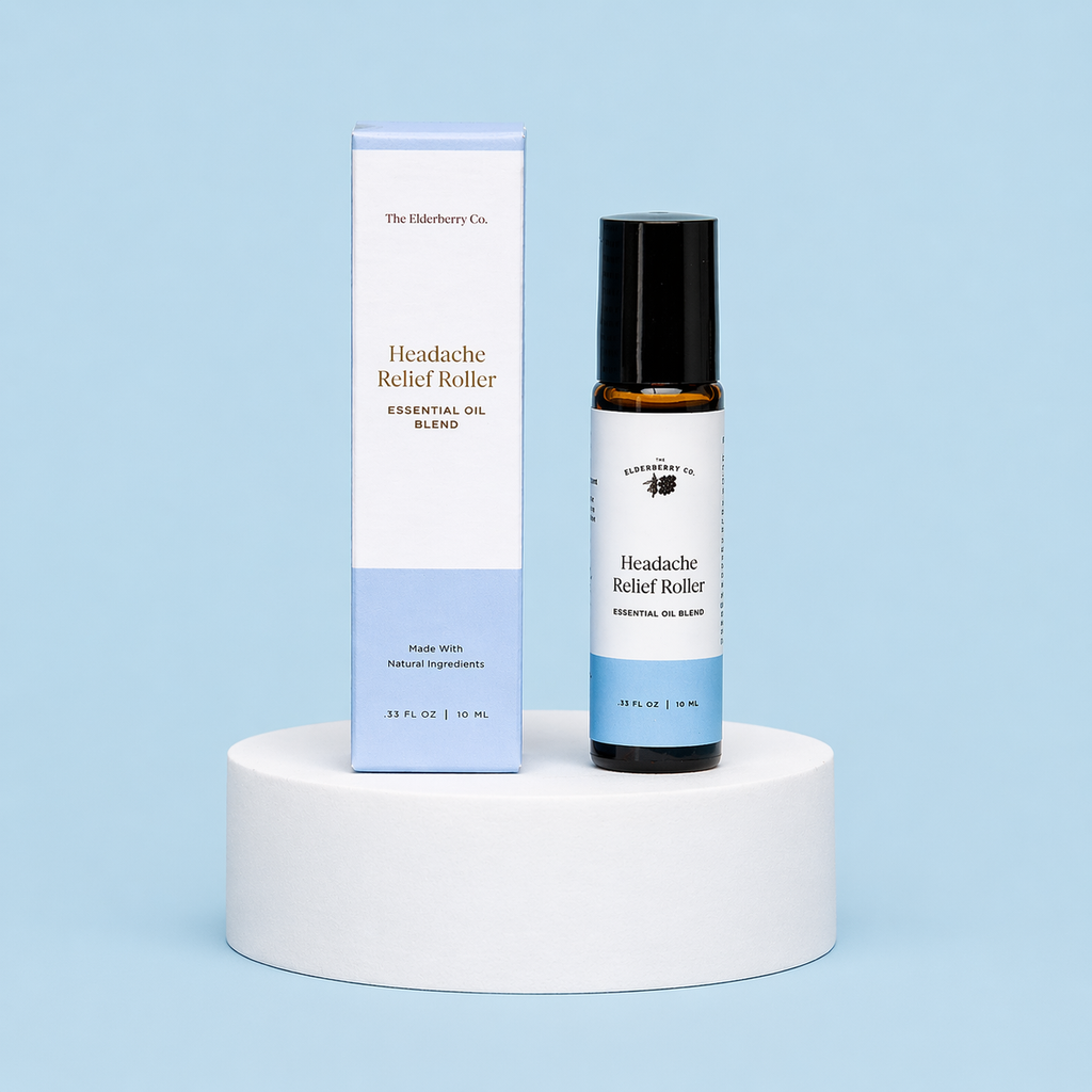 The Elderberry Co. Headache Relief Roller essential oil blend with its matching retail box displayed on a white pedestal against a soft blue background.